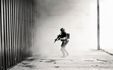 B&W photo of Geared-up male airsoft player walking through smoke
