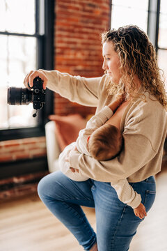 Mother multitasking while breastfeeding and holding camera