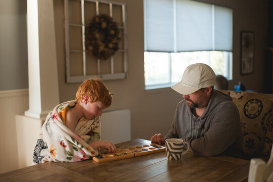 Father and son bonding over board game in cozy sunlit home setting