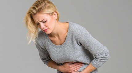 Woman bent forward, pressing her hands on stomach, showing symptoms of irritable bowel syndrome (IBS) or cramps.