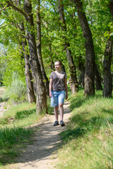 Obraz premium Teen girl a girl walks along a forest path, beautiful spring nature, green leaves, landscape