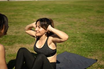 Woman doing sit-ups in park with personal trainer