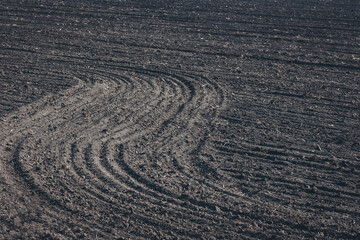 Naklejka premium Patterns of freshly plowed earth create a tapestry of textures in an agricultural field under the midday sun in early spring