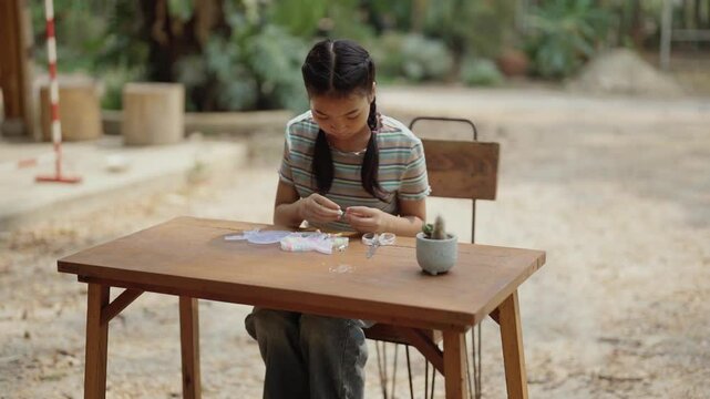 Asian girl making handmade necklace accessories
