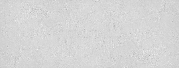 Large white grunge textured concrete wall background. The backdrop is a rough cement floor
