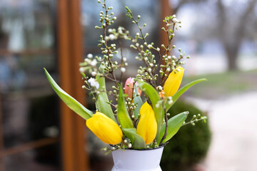 Vintage rustic vase of yellow tulips flowers on table. Traditional spring flower. Fresh red flowers...