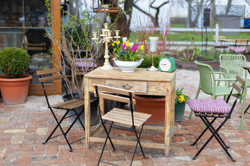 Empty cafe with terrace with table and chairs. Street vintage exterior of restaurant. Furniture for coffee street shop. Street with table with flowers and decor of cafe in garden. Cozy patio outdoor