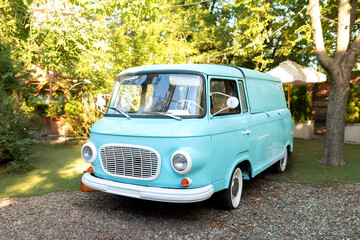 Old vintage bus in garden. Blue classic Transporter retro vehicle. Wedding auto decoration. Mint mini-bus in camping.	
