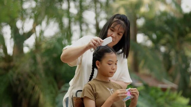 Asian mother braids her daughter's hair