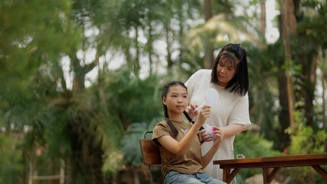 Asian mother braids her daughter's hair