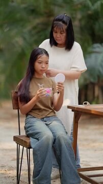 Asian mother braids her daughter's hair