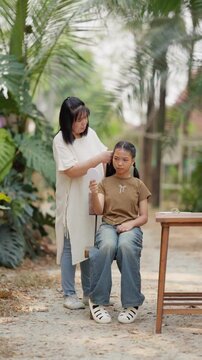Asian mother braids her daughter's hair