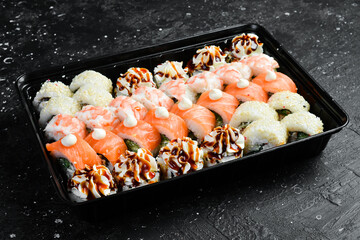 Sushi delivery. Sushi rolls with cheese and fish. Disposable tableware. On a wooden board.