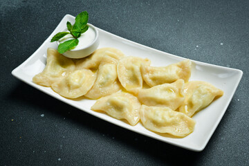 Traditional Ukrainian dumplings with salty cheese and potatoes. On a black stone background.