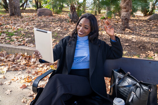 Businesswoman video calling with tablet in autumn park