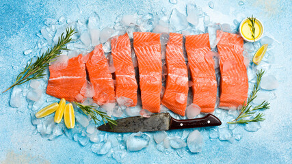 Fresh salmon fillet. Pieces of raw salmon fillet on ice. On a blue stone background. Top view.