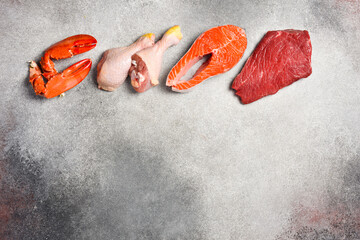 Set of various raw meats on a dark grunge background. beef, fish, lobster claws, pork and chicken. Free space for text. On a gray stone background.