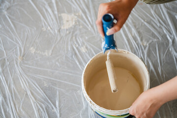 a beige can of paint with paint roller on floor