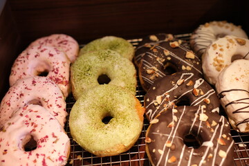 A variety of colorful donuts arranged in a box, featuring a mix of glazed, chocolate-coated, and sprinkled toppings. The assortment includes donuts with vibrant white, chocolate. High quality photo