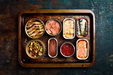 cans canned with different types of fish and seafood: fish, caviar, cod liver, sprats. Top view