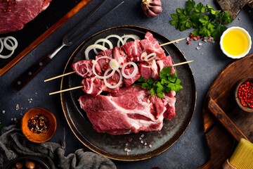 Raw pork kebab on wooden skewers. Preparation of meat dishes. On a gray stone background.