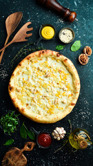 Classic pizza with chicken, pineapple and cheese. Cheese pizza. On a black stone background. Top view.