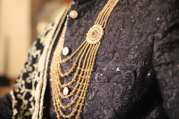 A close up if an Indian groom in a traditional wedding dress with Sherwani with sword in hand