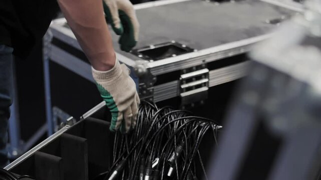 Worker coiling cables above transport case
