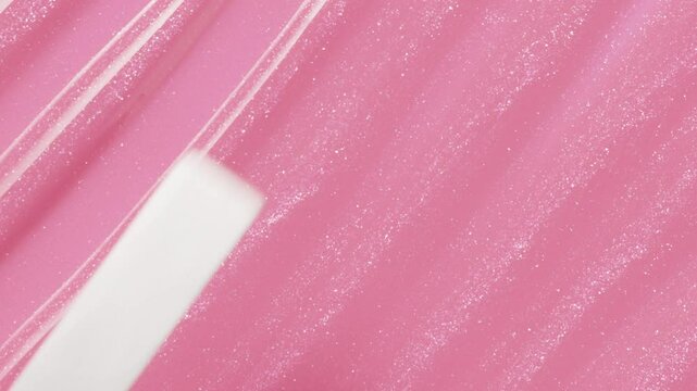 Close up of spatula smear pink lip gloss texture, texture stroke. Cosmetic product swatch