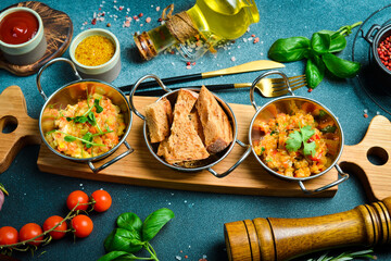 Stewed vegetables and brown bread. Cold snacks. Restaurant serving. Close up. On a dark stone background.