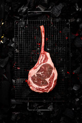 A raw aged Tomahawk steak is grilled over hot coals. Barbecue. Top view.