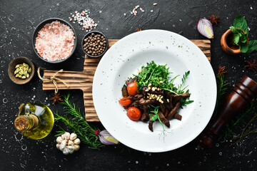 Fresh salad with veal: arugula, veal, pine nuts and eggplant. Healthy food. On a white plate. Rustic style.
