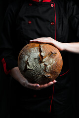 Female hands hold Fresh Sourdough Bread on black background. Top view.