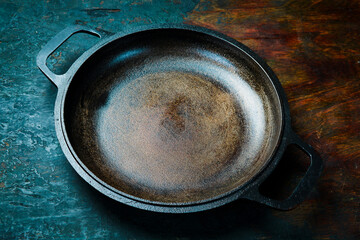 Vintage cast iron cooking pan. On a rustic background.
