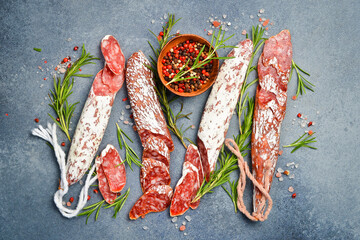 Fuet Salami cut in slices. Traditional Spanish sausage on a gray concrete background. Sliced...