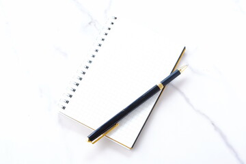 リング式のメモ帳とペンでデスクワークをしているイメージ
