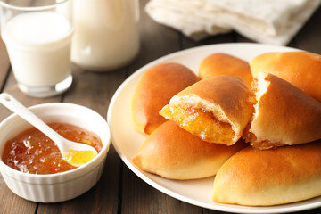 Tasty baked patties with orange jam on wooden table, closeup
