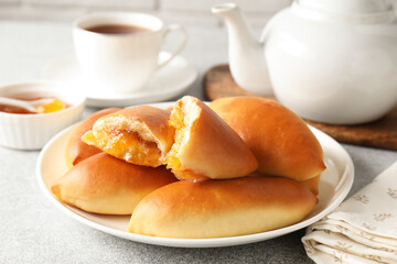 Tasty baked patties with orange jam on light grey table, closeup