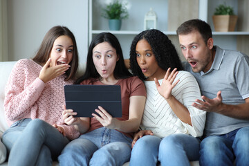 Surprised group of friends checking tablet at home