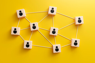 Wooden cubes with people icon linked to each other with lines on yellow background. online communication or social networking concept, 3d render
