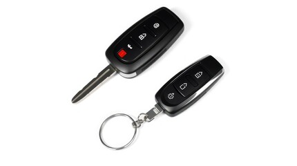 Modern car key and key fob with buttons are seen in a high-key studio shot on a white background.