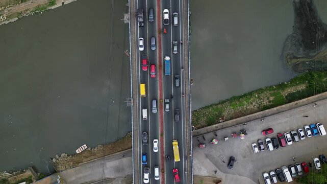 Topdown aerial of traffic over bridge spanning Marikina River, cars flowing in both directions