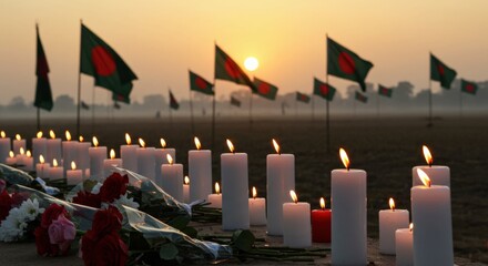 Solemn memorial scene with lit candles and flowers in the foreground, set against a field dotted with Bangladesh flags under a warm sunrise sky, symbolizing remembrance and tribute.