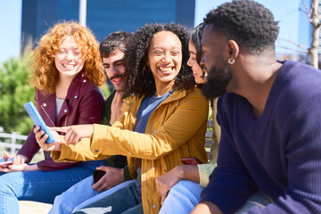 Group of diverse friends sharing a fun moment on smartphone outdoors