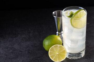 Gin Fizz cocktail with lime on black background. Copy space