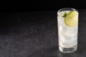 Gin Fizz cocktail with lime on black background. Copy space
