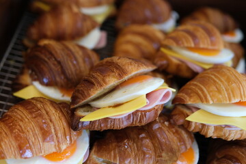 Tasty breakfast with croissant sandwiches with poached egg, avocado, soft cheese, mozzarella and tomato in a plate with forks on white background. High quality photo