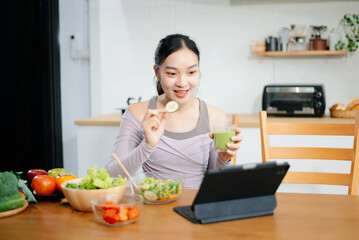Smiling woman in a modern kitchen with fresh fruits, veggies, blender, and juice, embracing clean...