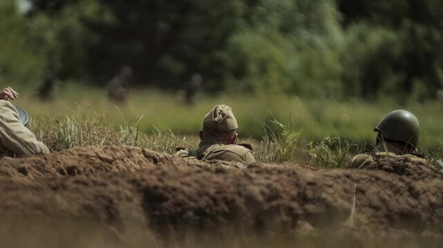 Red Army Soviet soldiers sit in trenches on defensive waiting for German troops to attack during Great Patriotic War battle simulation. Operation Bagration in Summer 1944. Historical reenactment. USSR