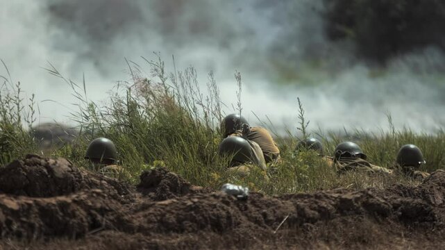 Soviet Red Army soldiers holding defensive position in trench line amidst tall grass observing battlefield. Great Patriotic War battle reconstruction. Stress. Concussion probability Artillery shelling